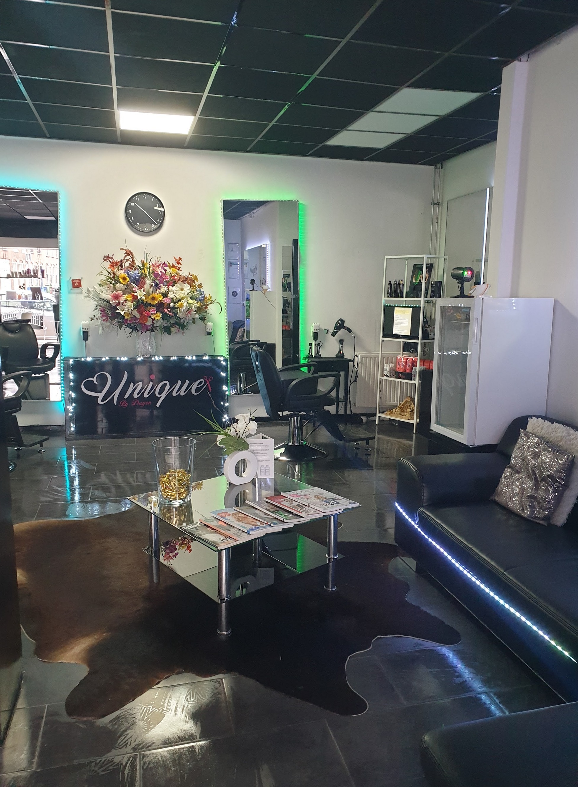 De salon van binnen: de balie met de letters Unique, bloemen en spiegels met ledverlichting